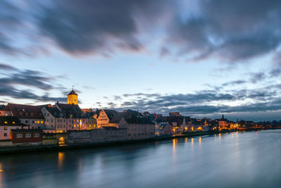 River in city against sky at sunset