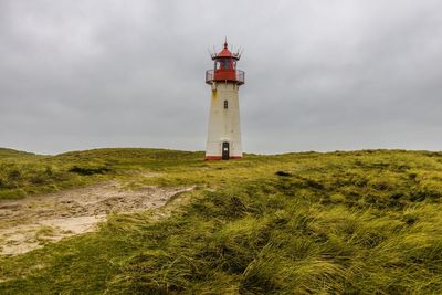 Lighthouse by sea against sky