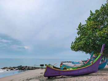 Boat moored on beach against sky