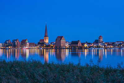 Reflection of illuminated buildings in city at dusk