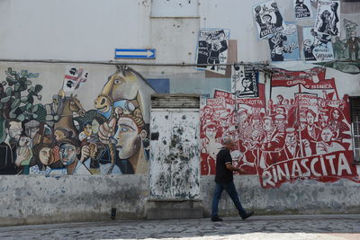 Full length of man standing by graffiti wall