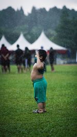 Full length of shirtless boy standing on field