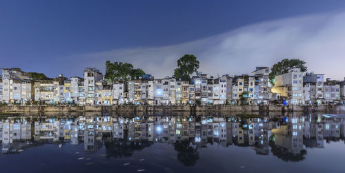 Reflection of buildings in lake against sky at night