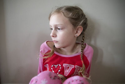 Blonde girl in french braids in pajamas looks sadly off-camera