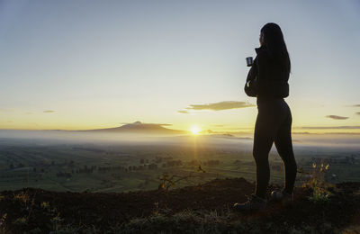Rear view of woman standing at beach against clear sky