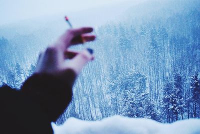Close-up of person holding cigarette on snow covered field