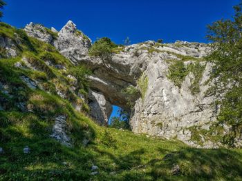 Low angle view of rocks against clear blue sky