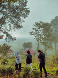 Rear view of people walking on landscape against sky