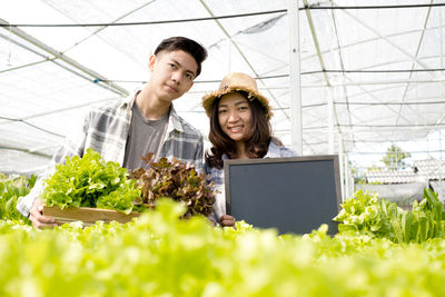 Portrait of young couple standing in greenhouse