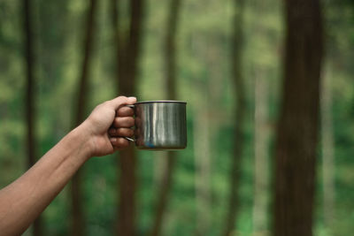 Close-up of person holding hand on table in forest