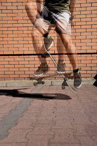 Double exposure image of man practicing stunt on skateboard against brick wall