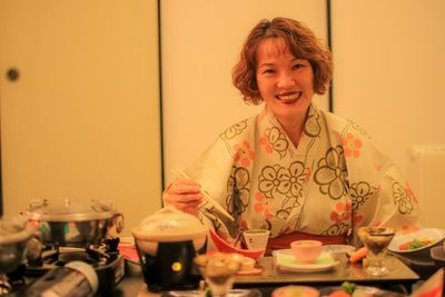 Portrait of happy woman having food at home