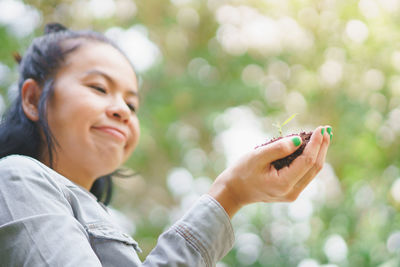 Portrait of woman holding mobile phone outdoors