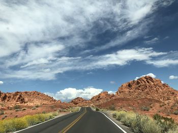 Road leading towards mountains against sky