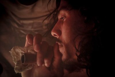 Close-up of young man looking away while holding smoking pipe