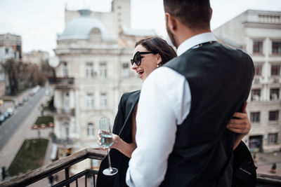 Midsection of man holding woman standing against building in city