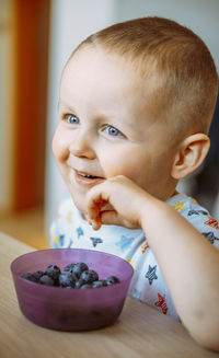 Portrait of cute baby boy eating blueberries at home