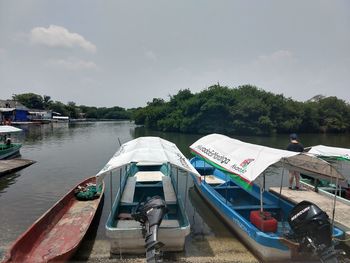 Boats moored in river against sky