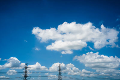 Low angle view of electricity pylon against blue sky