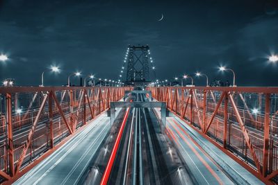 Light trails on illuminated city against sky at night