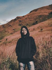 Portrait of man standing on field against mountain