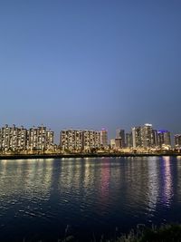 Illuminated buildings in city against clear sky