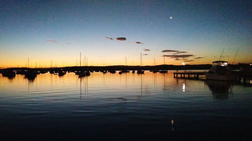 Silhouette boats in lake at sunset