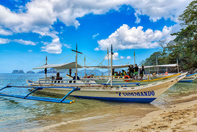 Sailboats moored on beach against sky