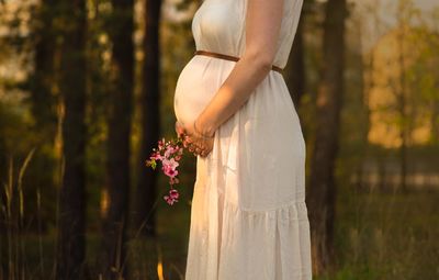 Side view of woman standing by flowering plants on field