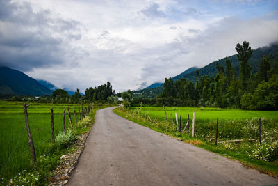 Road amidst field against sky