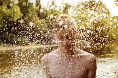 Water splashing on shirtless boy