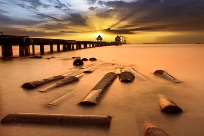 Scenic view of beach against sky at sunset