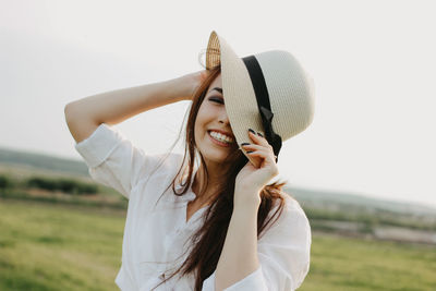 Woman wearing hat standing on field against sky