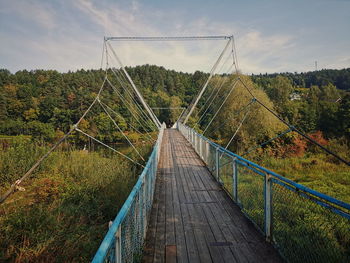 Footbridge amidst plants against sky