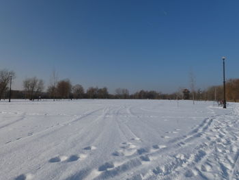 Snow covered field against clear sky during winter