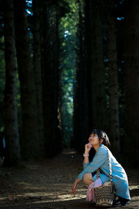 Side view of woman sitting in forest