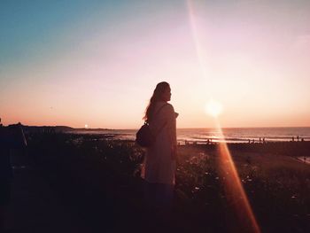 Man standing on beach against sky during sunset