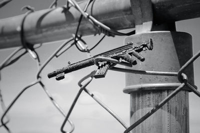 Low angle view of toy gun attached on chainlink fence