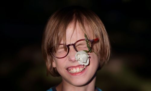 Close-up of smiling boy with flower hitting on face