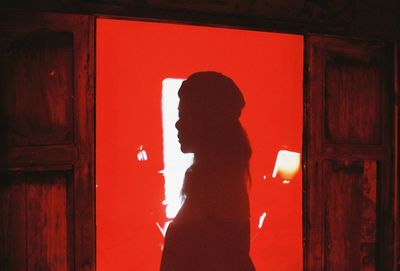 Side view portrait of silhouette woman standing against door
