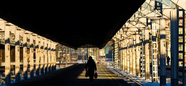 Silhouette woman with bags walking on railroad station platform