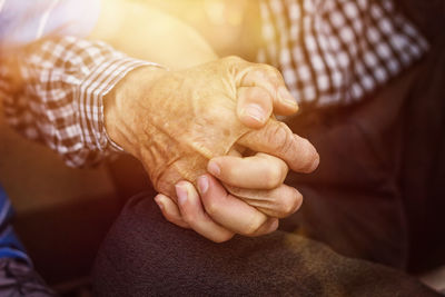 Cropped image of senior man and boy holding hands