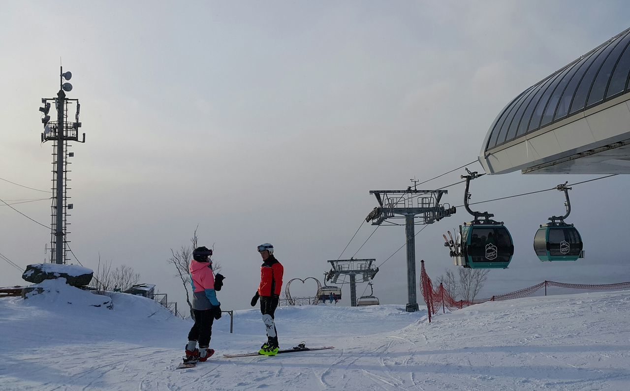 sky, winter, snow, cold temperature, weather, lifestyles, leisure activity, full length, men, transportation, hanging, cable, outdoors, low angle view, day, season, sport, safety, mode of transport