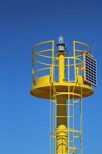 Low angle view of yellow tower against clear blue sky