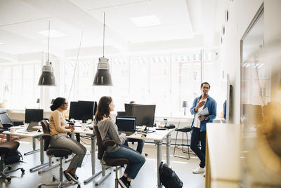 Computer programmer explaining code to colleagues during meeting in creative office