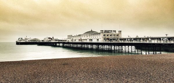 View of pier on beach against cloudy sky