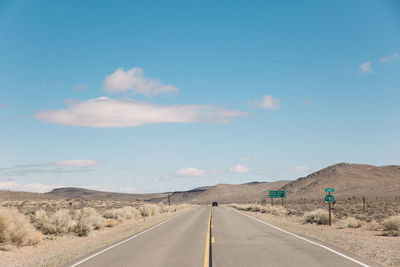 Road by desert against sky