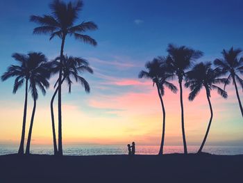 Silhouette palm trees on beach against sky during sunset