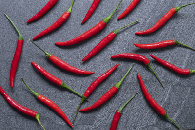 Several fresh red hot chili pepper on a dark black stone background, food ingredient concept, 