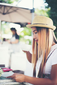 Woman drinking coffee while sitting at sidewalk cafe